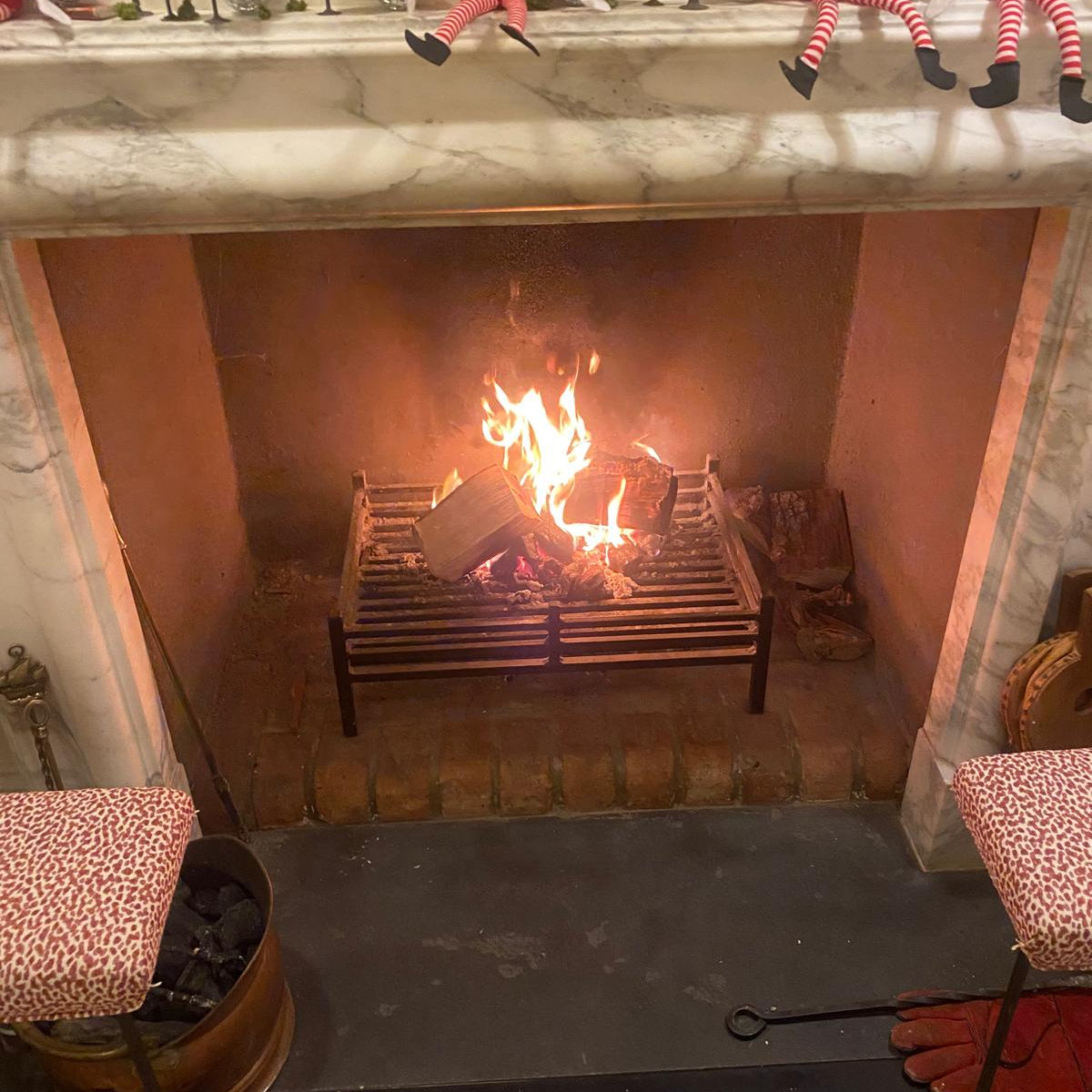 Fireplace with lit fire and Elves on the Shelf figurines on a mantel.