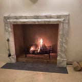 Fireplace with a lit fire inside, framed by marble mantel.